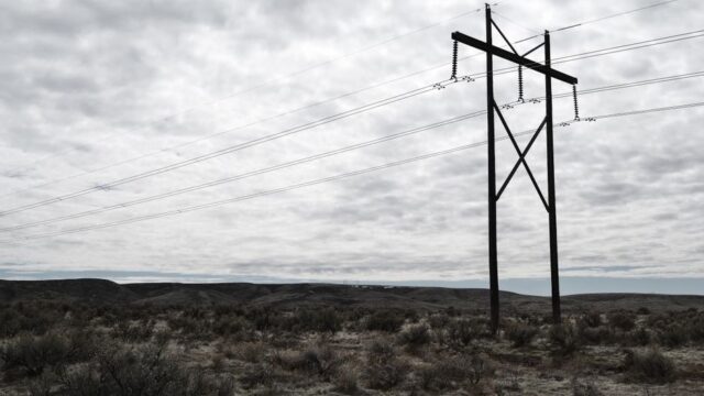 High voltage power lines stretch across a dramatic, cloudy sky landscape, embodying industrial beauty.