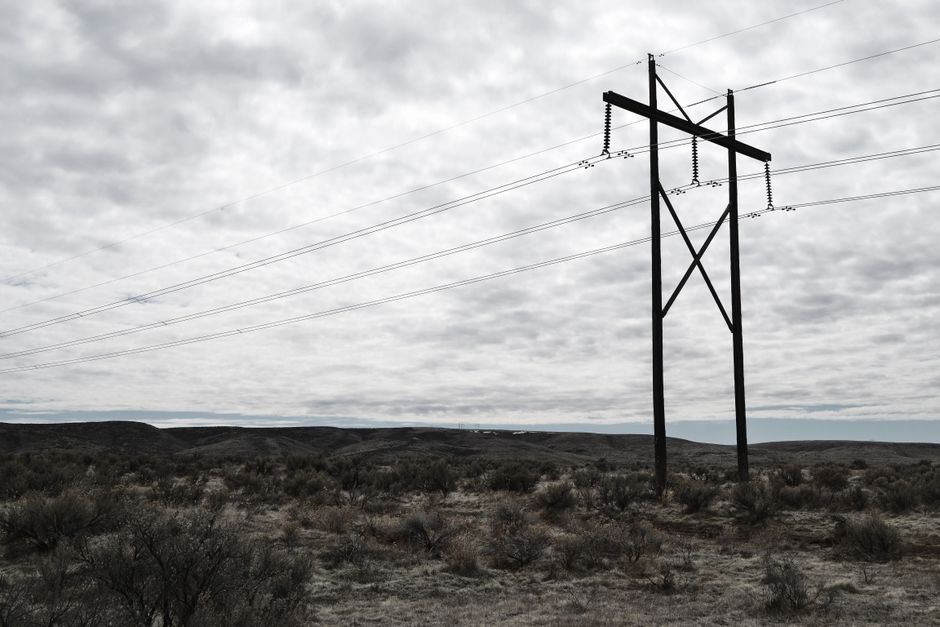 High voltage power lines stretch across a dramatic, cloudy sky landscape, embodying industrial beauty.