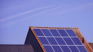 Close-up of solar panels on a tiled rooftop under a clear sky, showcasing renewable energy.