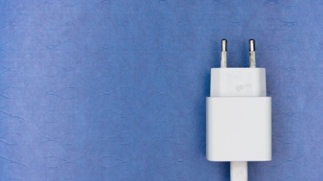 White electric charger plug on a blue textured surface, ideal for tech visuals.