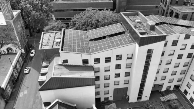 Black and white aerial view of buildings with solar panels, showcasing sustainable urban architecture.