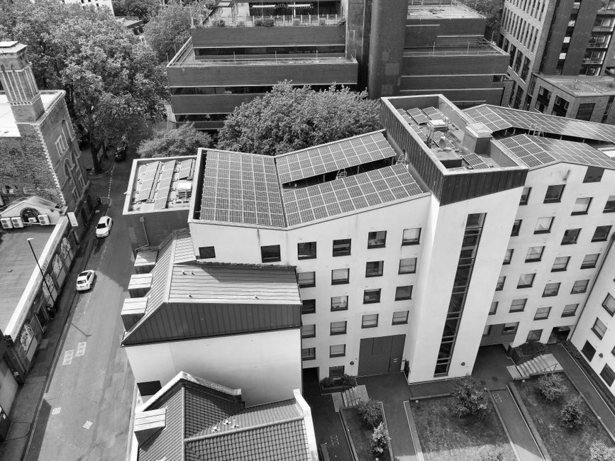 Black and white aerial view of buildings with solar panels, showcasing sustainable urban architecture.