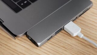 From above of modern USB hub connector under type c for laptop with plugged white cable on wooden table