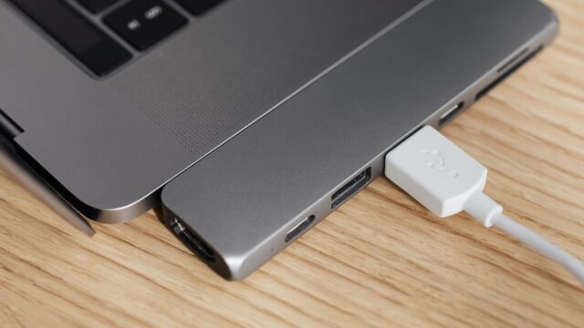 From above of modern USB hub connector under type c for laptop with plugged white cable on wooden table