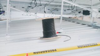 Coiled cable on a rooftop with solar panels, showcasing electrical installation for renewable energy.