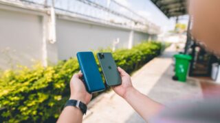 Close-up of a smartphone and power bank held in hands in an outdoor setting.