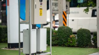 Modern electric vehicle charging station with greenery in an urban setting.
