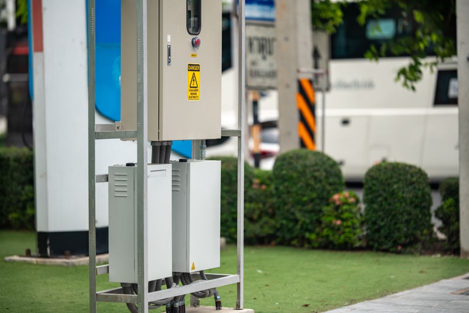 Modern electric vehicle charging station with greenery in an urban setting.