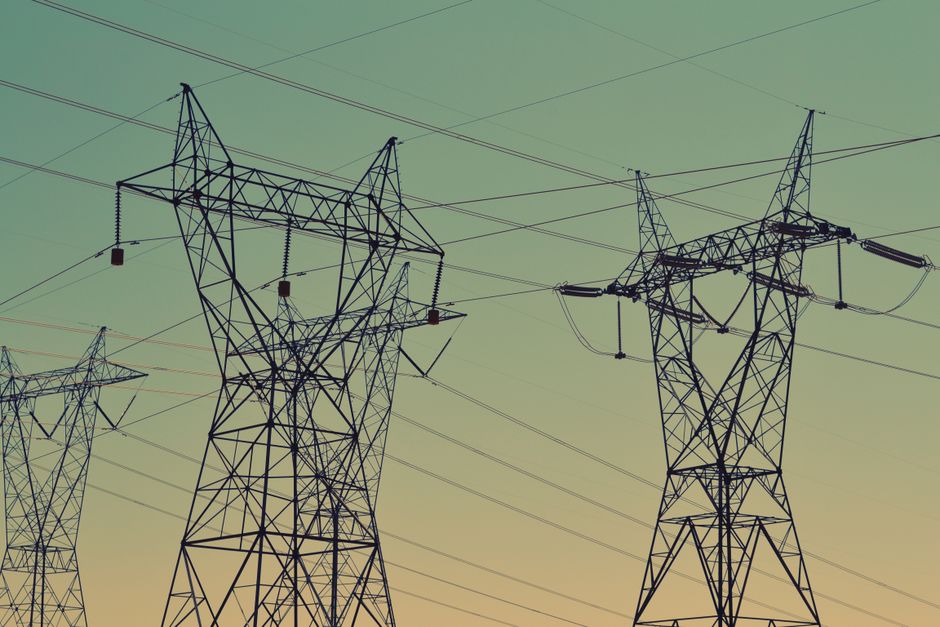 Silhouette of high voltage power lines against a twilight sky, illustrating energy infrastructure.