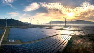 Aerial photograph capturing solar panels and wind turbines under a stunning sunrise. Sustainable energy landscape.
