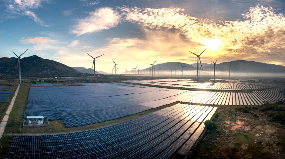 Aerial photograph capturing solar panels and wind turbines under a stunning sunrise. Sustainable energy landscape.