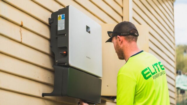 A skilled technician working on the installation of a solar inverter system outdoors. Energy efficiency solution.