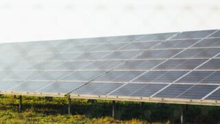 Expansive solar panel array harnessing clean energy in a sunny outdoor field scene.