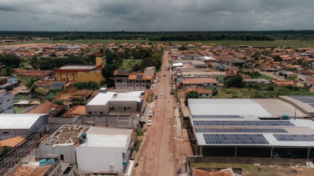 Drone shot capturing a townscape featuring solar panels on rooftops and a scenic landscape.