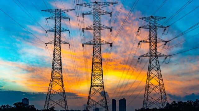 High voltage power lines against a dramatic sunset sky, symbolizing energy and technology.
