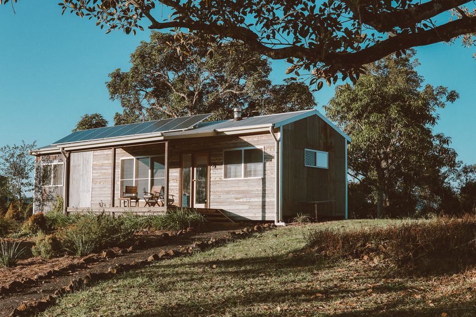 A charming wooden house in Australia featuring solar panels, surrounded by lush greenery.