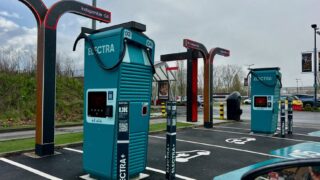 A modern electric vehicle charging station in a parking lot on a cloudy day.
