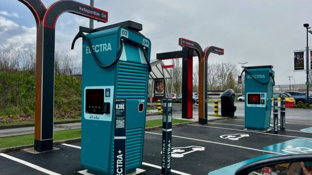 A modern electric vehicle charging station in a parking lot on a cloudy day.