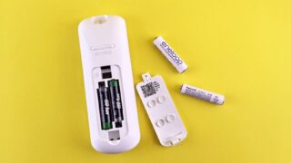 Close-up of remote control and batteries on vibrant yellow surface.