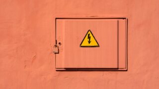 Bright yellow high voltage warning sign on a locked electrical box.