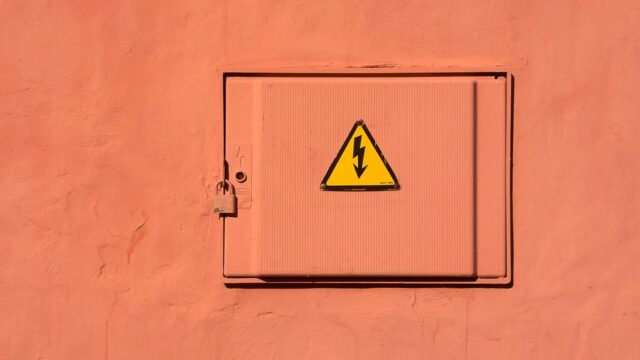 Bright yellow high voltage warning sign on a locked electrical box.