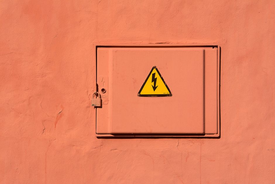 Bright yellow high voltage warning sign on a locked electrical box.