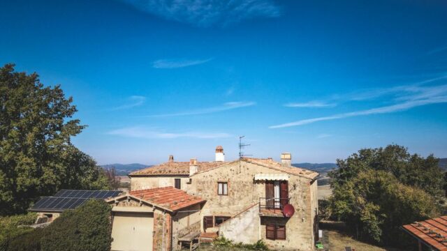 Beautiful rustic house with solar panels amidst nature under a clear blue sky. Perfect for sustainable living.