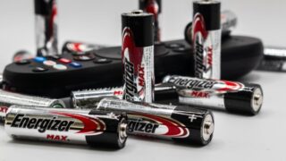 Close-up of multiple Energizer AA batteries and a remote control on a white surface.