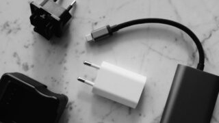 Composition of various modern charging units with adapter and small black external battery with short cable placed on white marble table