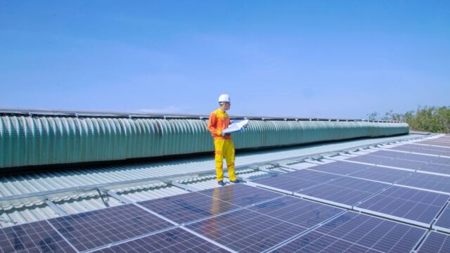 Technician examining solar panels on a rooftop, emphasizing renewable energy.