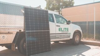 Solar panel leaning against utility truck promoting clean energy installation.
