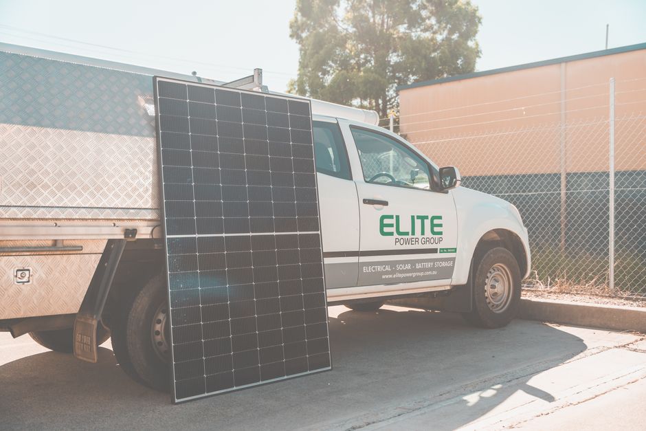 Solar panel leaning against utility truck promoting clean energy installation.