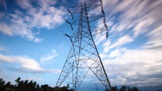 Dramatic view of a high voltage transmission tower set against a dynamic cloudy sky, showcasing modern energy infrastructure.