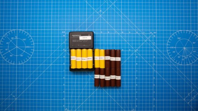 Top view of batteries on a blue grid design surface with a charger, showcasing organization and technology.