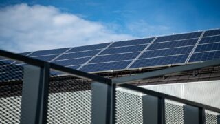 Close-up view of modern solar panels on a rooftop against a clear blue sky, representing clean energy.