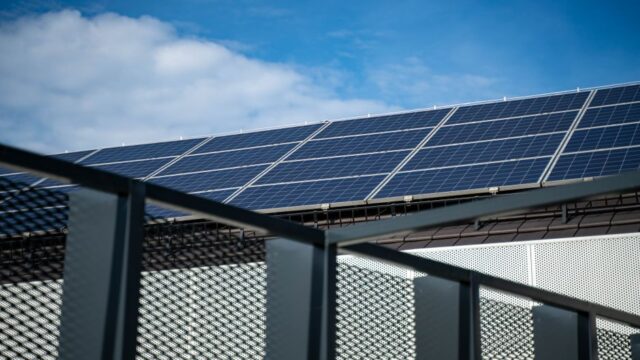 Close-up view of modern solar panels on a rooftop against a clear blue sky, representing clean energy.
