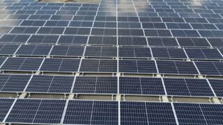 A large solar panel array on a sunny day in an open green field.