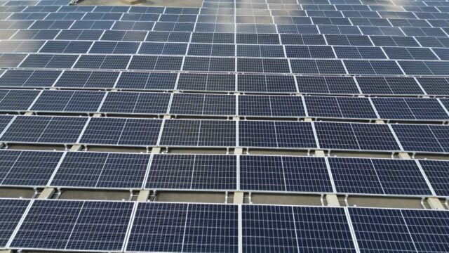 A large solar panel array on a sunny day in an open green field.
