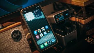 Smartphone and digital charging station on a desk with Klipsch speaker visible.