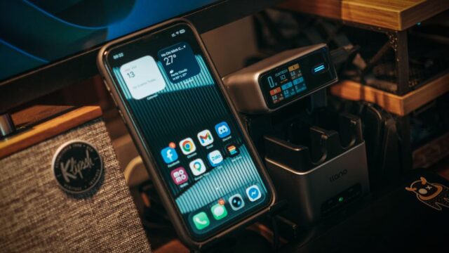 Smartphone and digital charging station on a desk with Klipsch speaker visible.