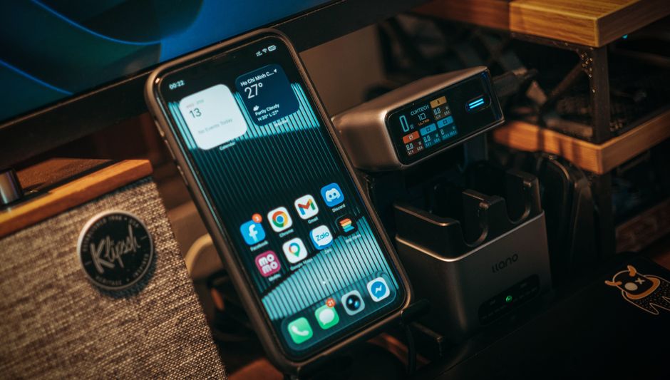 Smartphone and digital charging station on a desk with Klipsch speaker visible.