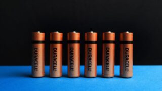 A lined up set of AA batteries with black and blue background.