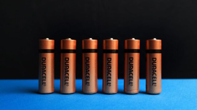 A lined up set of AA batteries with black and blue background.