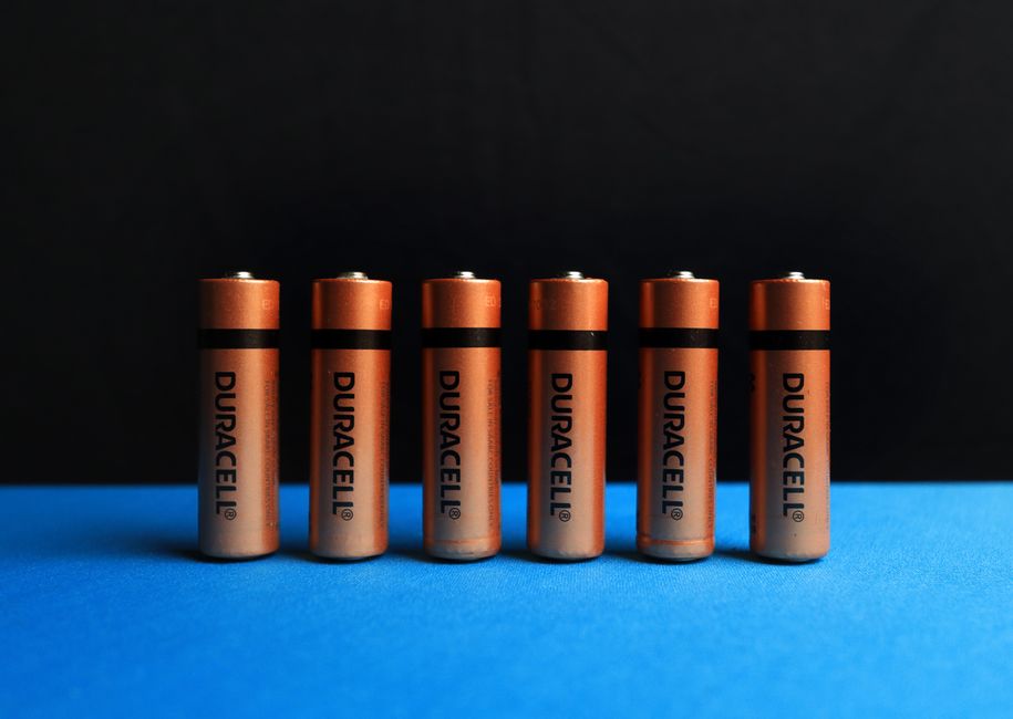 A lined up set of AA batteries with black and blue background.