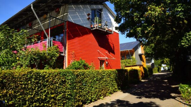 Contemporary solar-powered house in Freiburg surrounded by lush gardens, showcasing eco-friendly architecture.