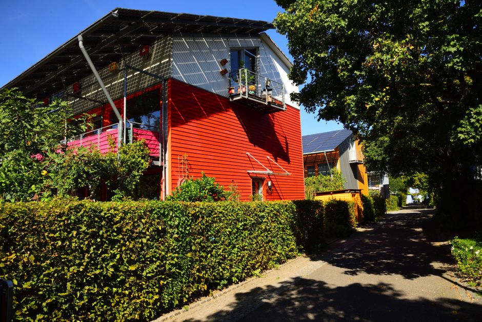 Contemporary solar-powered house in Freiburg surrounded by lush gardens, showcasing eco-friendly architecture.