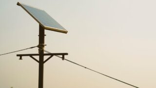 A single solar panel mounted on a tall post against a clear sky, symbolizing renewable energy.