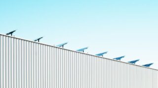 Corrugated steel building with solar panels under a clear blue sky, emphasizing sustainability.