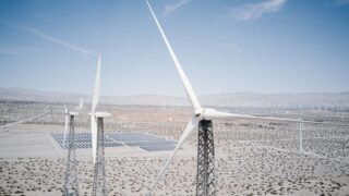 Wind turbines and solar panels generating renewable energy in a desert landscape.