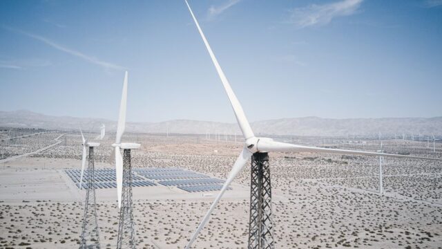 Wind turbines and solar panels generating renewable energy in a desert landscape.